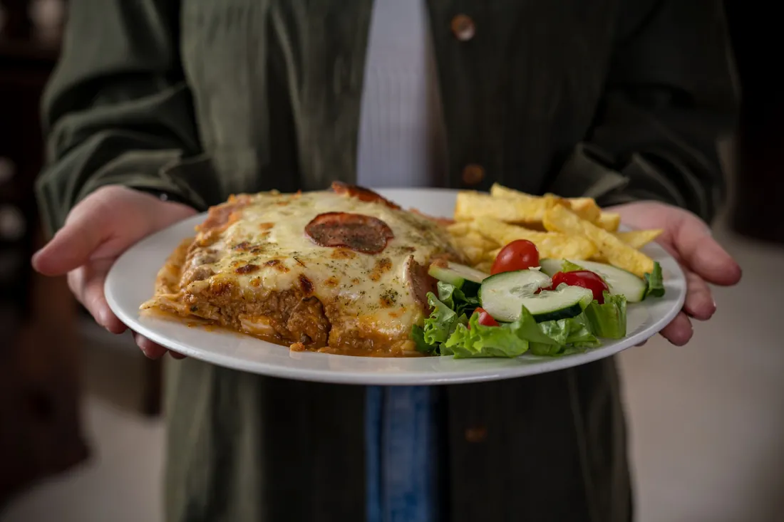 Lasaña con papas fritas y ensalada lista para servir