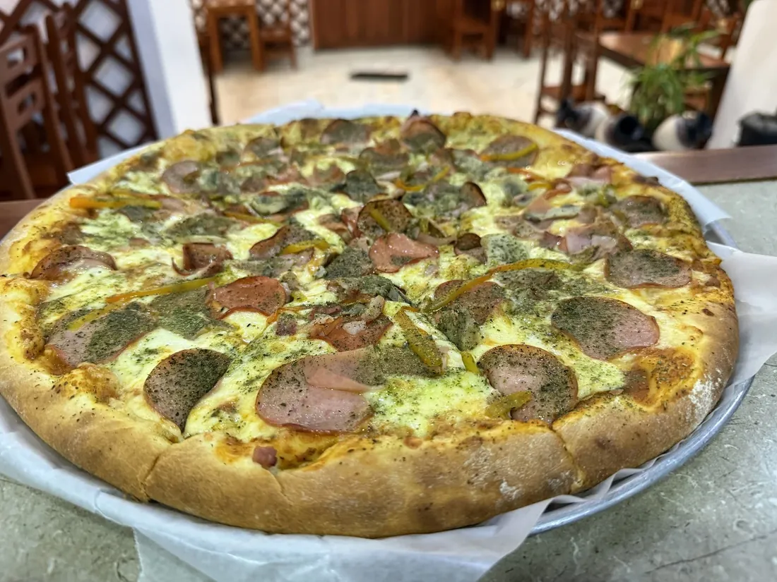 Pizza con salami, jamón y pimiento recién salida del horno