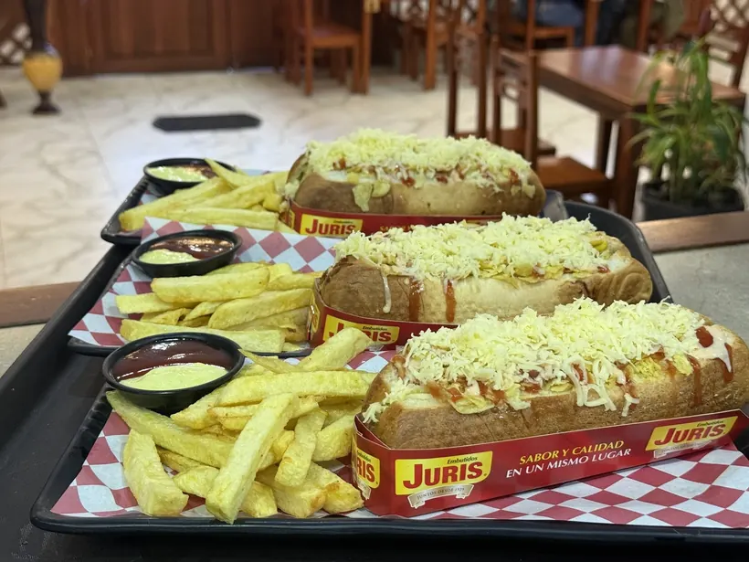 Tres hot dogs con queso rallado y papas fritas